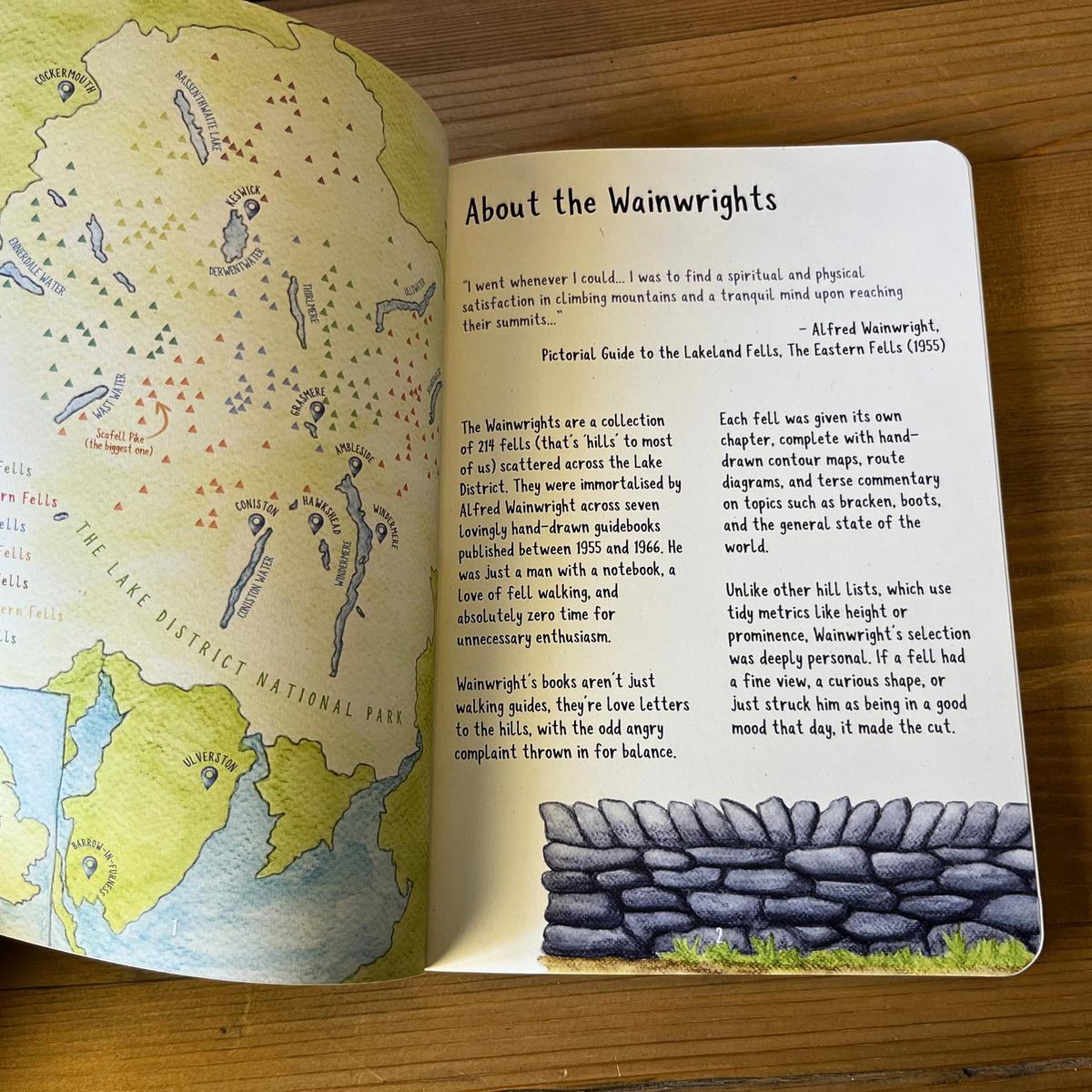 Open Wainwright Journal with a map and text about the Wainwrights on a wooden surface
